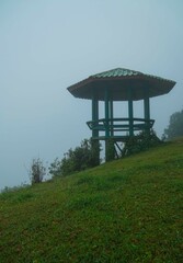 A small green pavilion sits on a grassy hillside