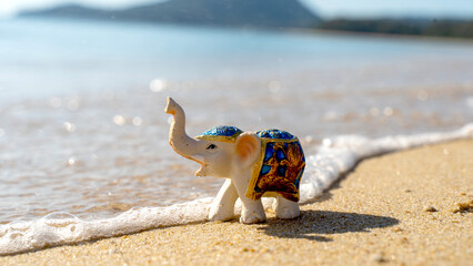 Elephant figurine on a sandy beach/ vacation and travel concept