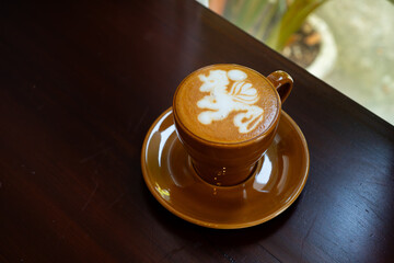 cafe latte with unicorn latte art, served on brown porcelain cup, in a cafe environment