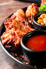 Close-up of crispy fried chicken served with sauces and garnishes on a dark plate.