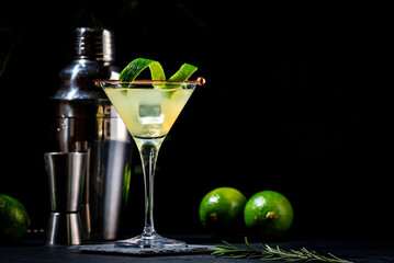 Classic alcoholic cocktail with vodka, syrup, lime, juice and ice in martini glass, dark background