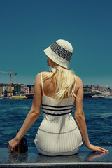 A young girl sits on the edge of an embankment in the Bosphorus Strait