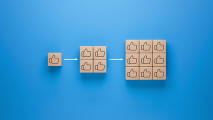 Wooden blocks with thumbs up icon on blue background, approval and success multiplication represented by increasing blocks, social media likes and positive feedback concept
