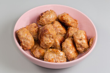Prepared meat patties in pink bowl on a gray background