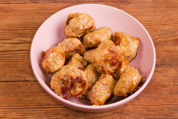 Prepared meat patties in pink bowl on a rustic table