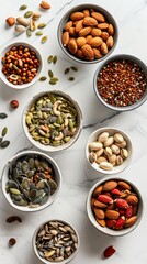 Top view of assorted nuts and seeds in bowls on a white marble surface. Highlighting nutritious ingredients for a healthy diet and balanced nutrition