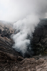 Picture of Bromo's crater with smoke. Bromo volcano in eruption. Located on Java island in Indonesia. Hike on top of a volcano, tourism attraction in Asia.