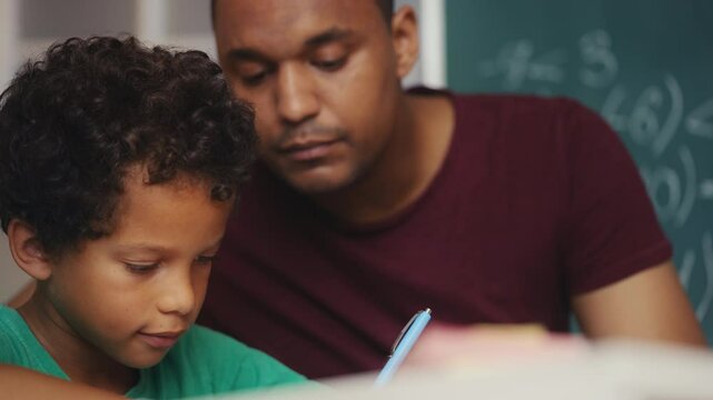 Caring dad helping son to solve math equations, homeschooling, parental guidance