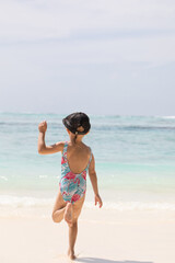 Young girl running joyfully on the beach, white sand, vitamin d, holidays with children, summer holidays