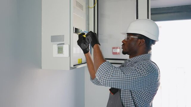 African american electrician worker checking, repair, maintenance operation electric system in office