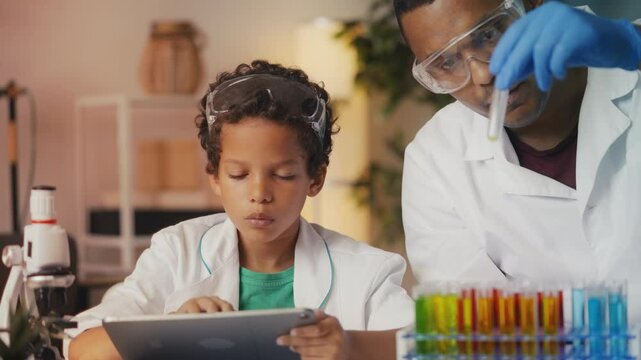 African American father and son observe reaction in test tube, playing science