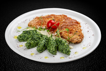 Chicken schnitzel served with sauce, accompanied by broccoli and cheese fritters.