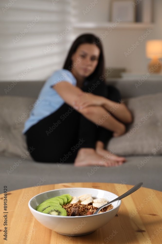 Canvas Prints Eating disorder. Sad woman sitting on sofa indoors, focus on granola, kiwi and banana