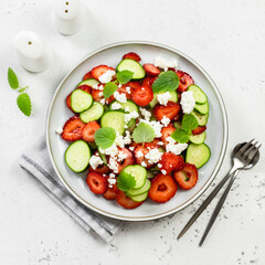 Refreshing mint cucumber strawberry feta cheese salad on plate. Top view, flat lay, copy space.