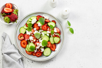 Refreshing mint cucumber strawberry feta cheese salad on plate. Top view, flat lay, copy space.