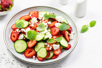 Summer refreshing cucumber strawberry feta cheese salad on plate. Top view, flat lay, copy space.
