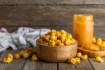 Sweet caramel popcorn in a bowl on a wooden background. Salted caramel popcorn. Caramel sauce. Close up. Topping. Place for text. Copy space