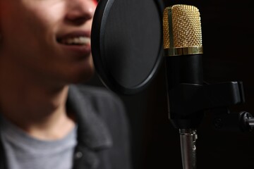 Vocalist singing into microphone in professional record studio, closeup