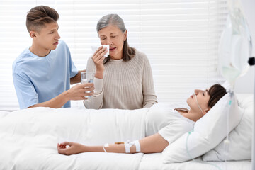 Obraz premium Coma patient. Sad relatives near sleeping young woman in hospital