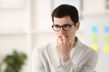 Embarrassed young man in glasses in office