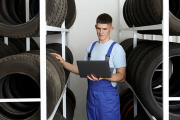 Young man with laptop near car tires in auto store © New Africa