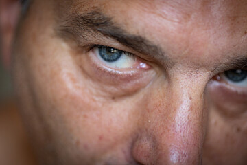 Close-up portrait of a mature man gazing into the camera with his blue eyes.