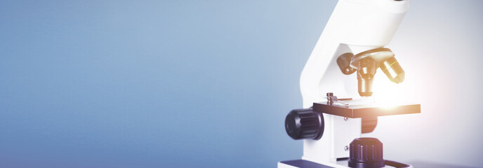 Naklejka premium Microscope on blue background, closeup. Banner design with space for text