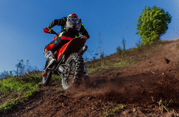 Professional enduro bike rider on action, dirt ride on the muddy track. Motocross sport. 