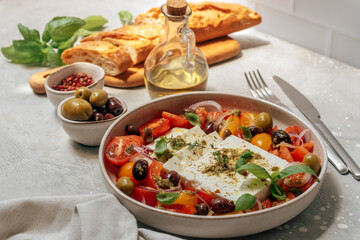 Healthy lunch or dinner with fresh feta cheese salad with organic tomatoes with olives and basil, olive oil and aromatic herbs
