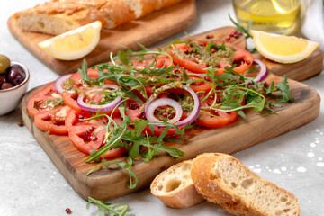 Tomatoes salad Organic tomatoes carpaccio with pesto sauce and arugula, an on-trend summer healthy eating salad