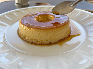 Close-up of a smooth, creamy flan drizzled with caramel sauce.