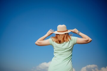 Woman tourist sky sea. Happy traveler woman in hat enjoys vacation raised her hands up