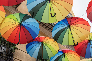 Colorful umbrellas hanging in the street. Various colorful umbrellas hanging above a street during...