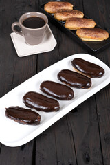 Chocolate Eclairs on White Plate with Coffee Cup: Delicious French Pastries and Hot Beverage for Gourmet Dessert or Cafe Menu Background