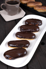 Chocolate Eclairs on White Plate with Coffee Cup: Delicious French Pastries and Hot Beverage for Gourmet Dessert or Cafe Menu Background