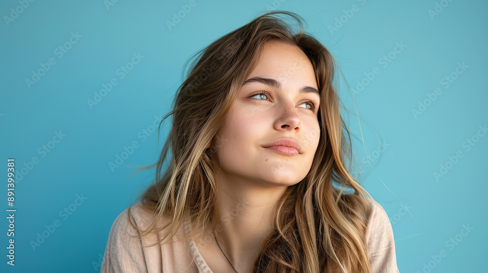 Wall mural young woman isolated over blue background relaxed thinking about something looking at a copy space