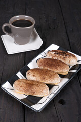 Homemade Cinnamon Sugar Pastries with Coffee: Rustic Breakfast Scene on Dark Wooden Table, Traditional Baked Goods and Hot Beverage for Cozy Morning