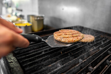 Close-up view of grilled burger patties being flipped on a grill