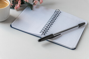 cup of coffee, notepad, pen and pink flower on white table mock up
