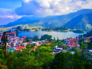 A breathtaking view of Sarangan Lake, nestled amidst lush green hills and quaint village houses. 
