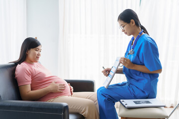 Obraz premium Pregnant mothers meet the nurse at the clinic as scheduled, reviewing their medical history and discussing symptoms. Sitting on the sofa, they report headaches, nausea, and back pain to the nurse.