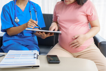 Pregnant mothers meet the nurse at the clinic as scheduled, reviewing their medical history and discussing symptoms. Sitting on the sofa, they report headaches, nausea, and back pain to the nurse.
