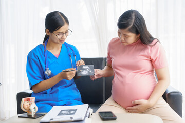 Pregnant mothers meet the nurse at the clinic as scheduled, reviewing their medical history and discussing symptoms. Sitting on the sofa, they report headaches, nausea, and back pain to the nurse.