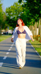 A young redhead woman spends time in a scenic park on a summer day