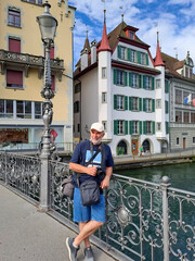 Mature man with camera on the bridge over the river Reuss in the city of Lucerne