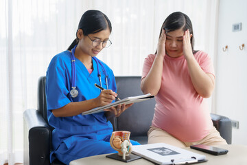 Obraz premium Pregnant mothers meet the nurse at the clinic as scheduled, reviewing their medical history and discussing symptoms. Sitting on the sofa, they report headaches, nausea, and back pain to the nurse.