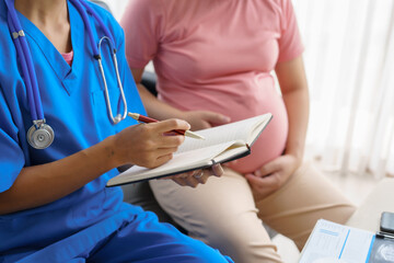 Pregnant mothers meet the nurse at the clinic as scheduled, reviewing their medical history and discussing symptoms. Sitting on the sofa, they report headaches, nausea, and back pain to the nurse.