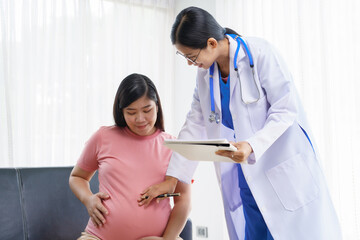 Obraz premium A pregnant woman sits on the sofa in the clinic. The doctor examines her abdomen and reviews the ultrasound results. Offering encouragement, the doctor holds her hand, providing support and care.