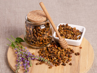 Bee bread in glass jar and bowl on table, healthy food supplement