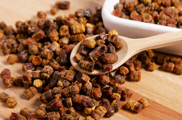 Fresh bee bread on spoon on wooden table, close-up
